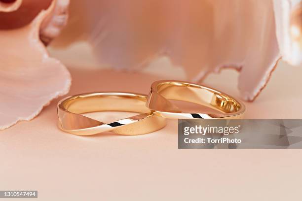 pair of stylish gold wedding rings on beige background - coniugi foto e immagini stock
