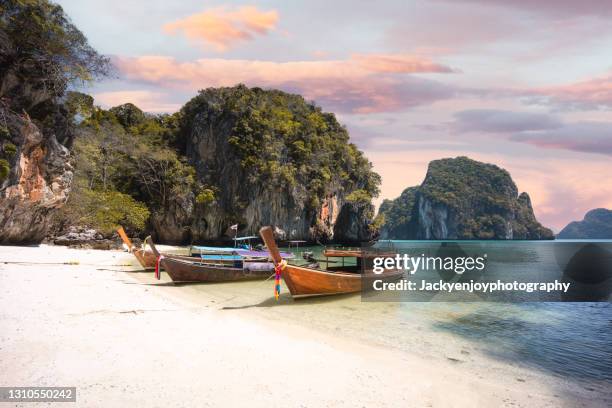 long tail boat on koh lao la ding beach in krabi during a sunny day , thailand , asia - phuket beach stock-fotos und bilder