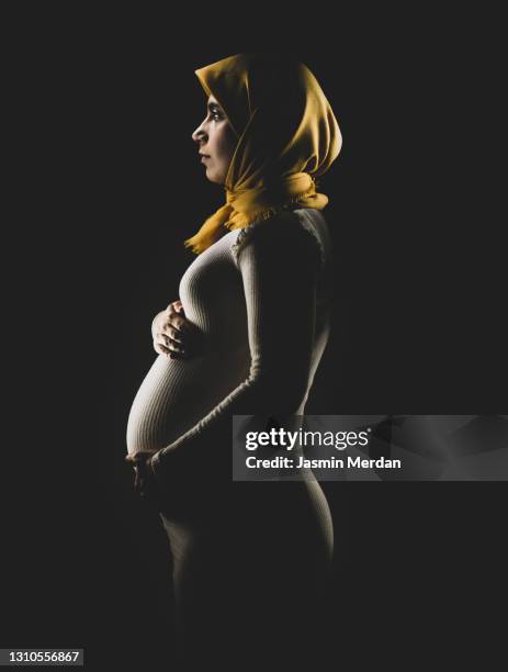 pregnant muslim woman embracing her belly - arab woman silhouette stock pictures, royalty-free photos & images