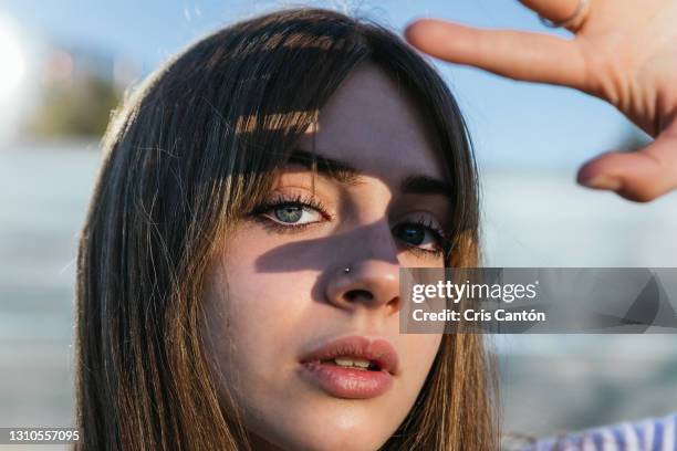 teenager girl outdoors looking at camera with sunlight on her eyes - smart cities stockfoto's en -beelden