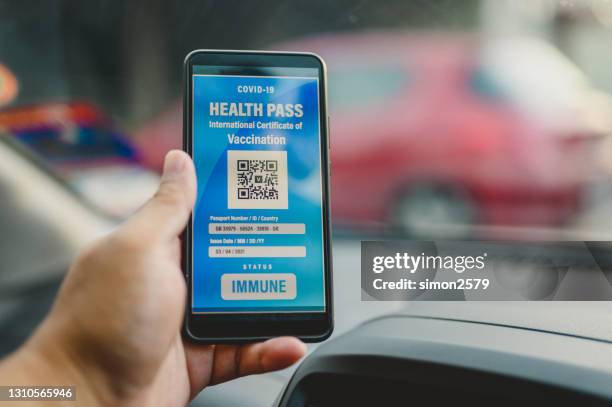 a man holding smartphone with digital certificate of covid-19 vaccination - covid 19 vaccine card stock pictures, royalty-free photos & images