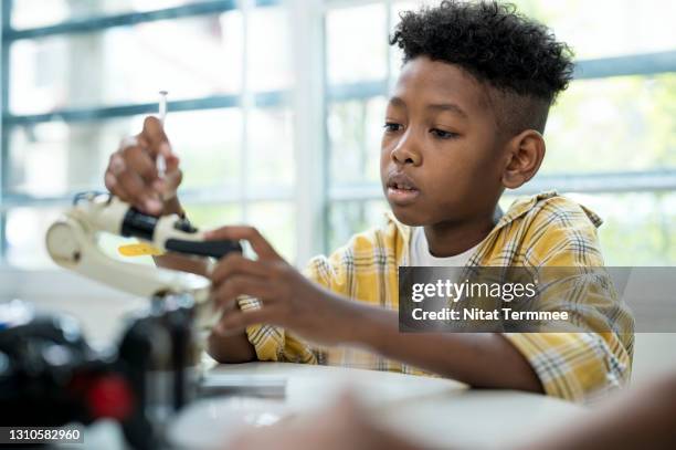 genius school boy african american in technology class, while practice robot arm assembly and program coding. - boy thailand stock-fotos und bilder