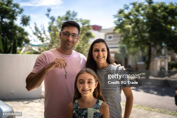 retrato de familia que muestra la llave de la nueva casa - family in front of home fotografías e imágenes de stock