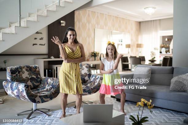 mother and daughter dancing in front of laptop at home - kid listening stock pictures, royalty-free photos & images