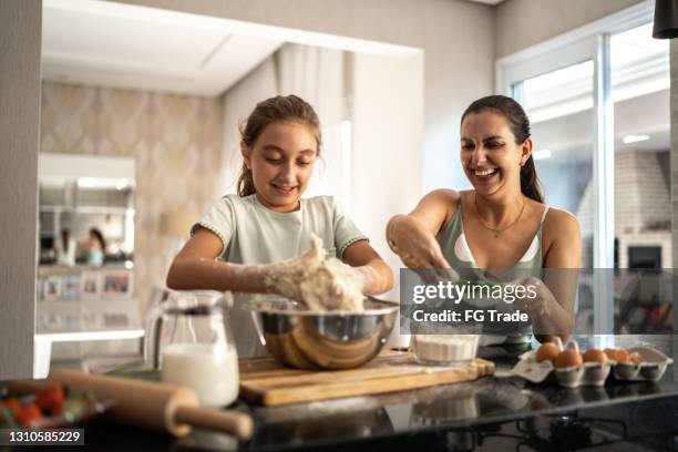 mother and daughter preparing a bread together at home - mother daughter cooking stock pictures, royalty-free photos & images