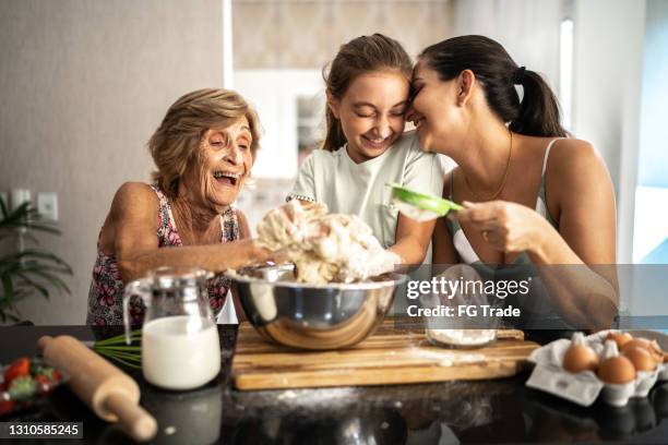 mehrgenerationenfamilie bereitet brot/kuchen zu hause zu - woman back stock-fotos und bilder