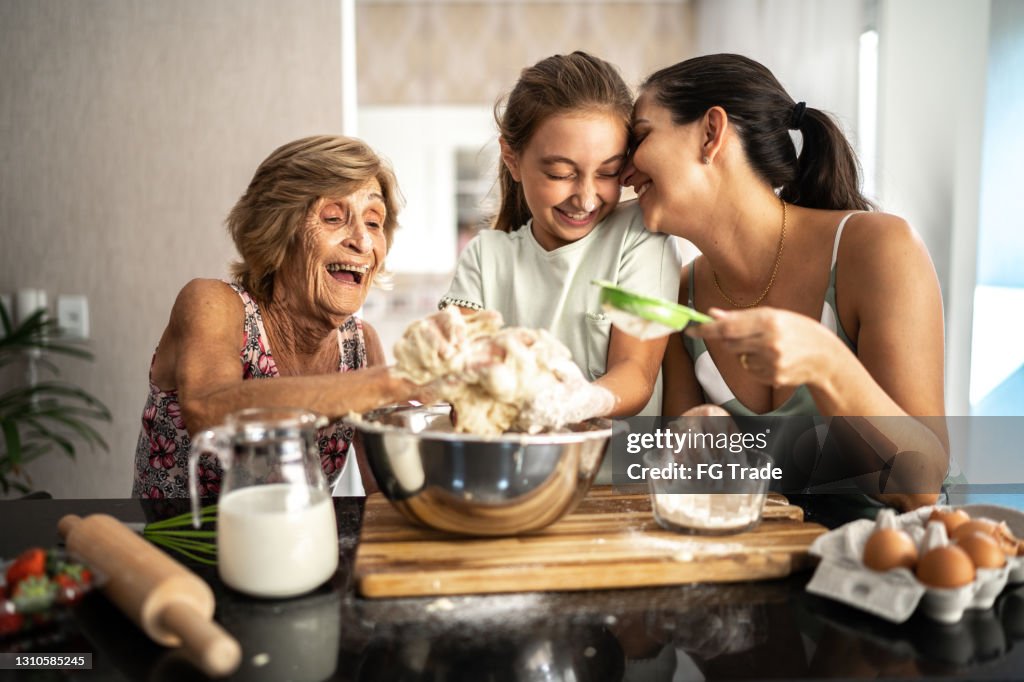 Famiglia multi-generazione che prepara un pane / torta a casa