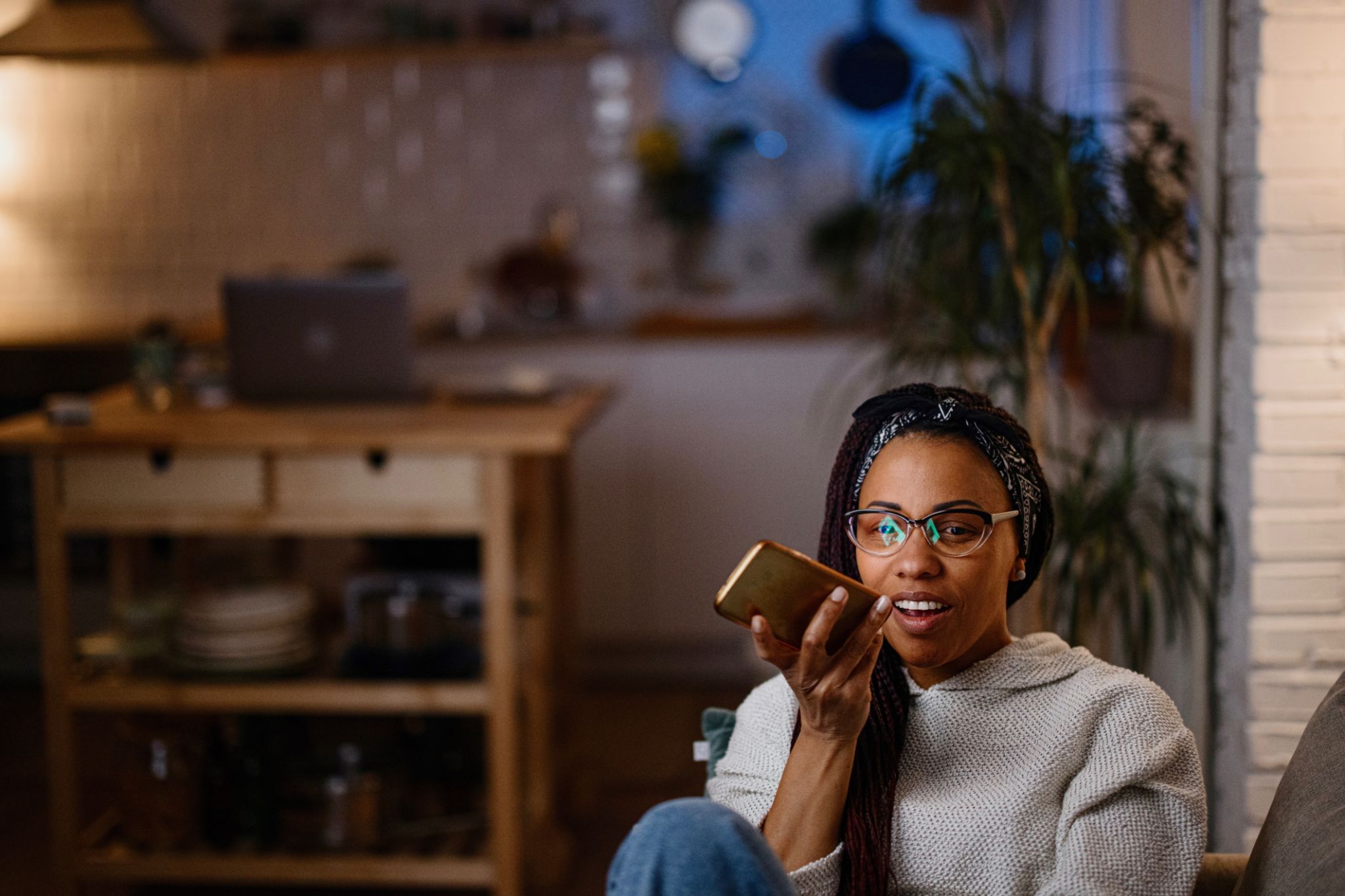 Woman using voice assistant on smart phone in her home late at night Woman using voice assistant on smart phone in her home late at night