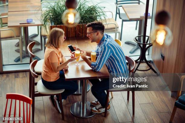 high angle view of a young caucasian couple having fun on their date in a coffee shop - telephone number stock pictures, royalty-free photos & images