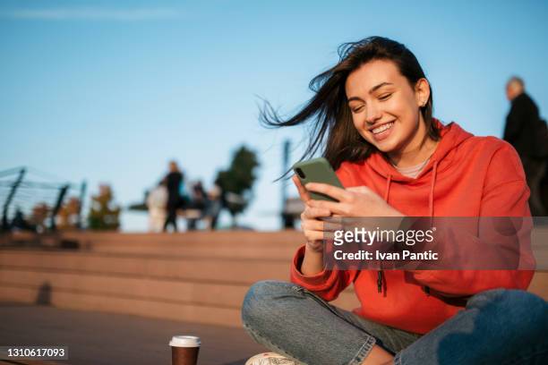 bella giovane donna caucasica che usa uno smartphone - red shirt foto e immagini stock