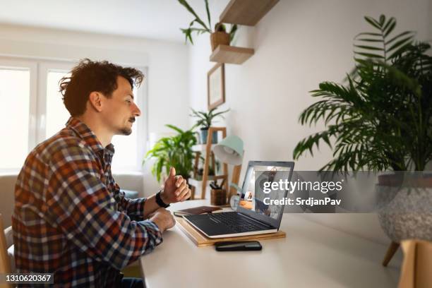 man video conferencing with his doctor on a laptop at home - doctor zoom stock pictures, royalty-free photos & images