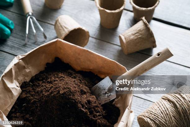 planting flowers, vegetables or fruits. transplanting a houseplant. growing organic farm products. equipment for botany. soil or earth in a paper eco-friendly bag and a small garden shovel. empty peat pots. fertilizer or chernozem for home gardening. - peat stock pictures, royalty-free photos & images