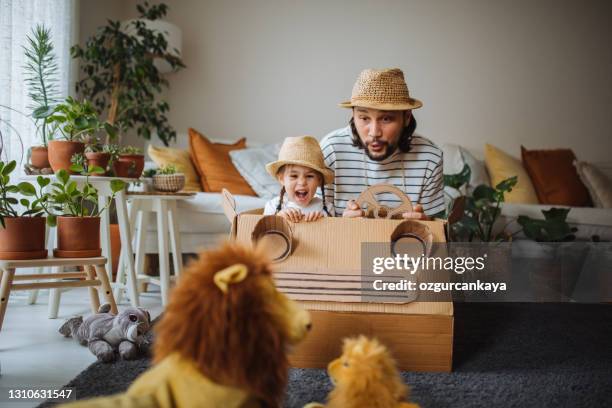 tochter und vater sind auf safari zu hause mit einem handgefertigten kartonwagen - familie zoo stock-fotos und bilder