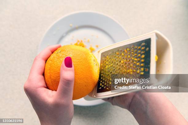 zesting an orange using a metal grater, - sabor - fotografias e filmes do acervo