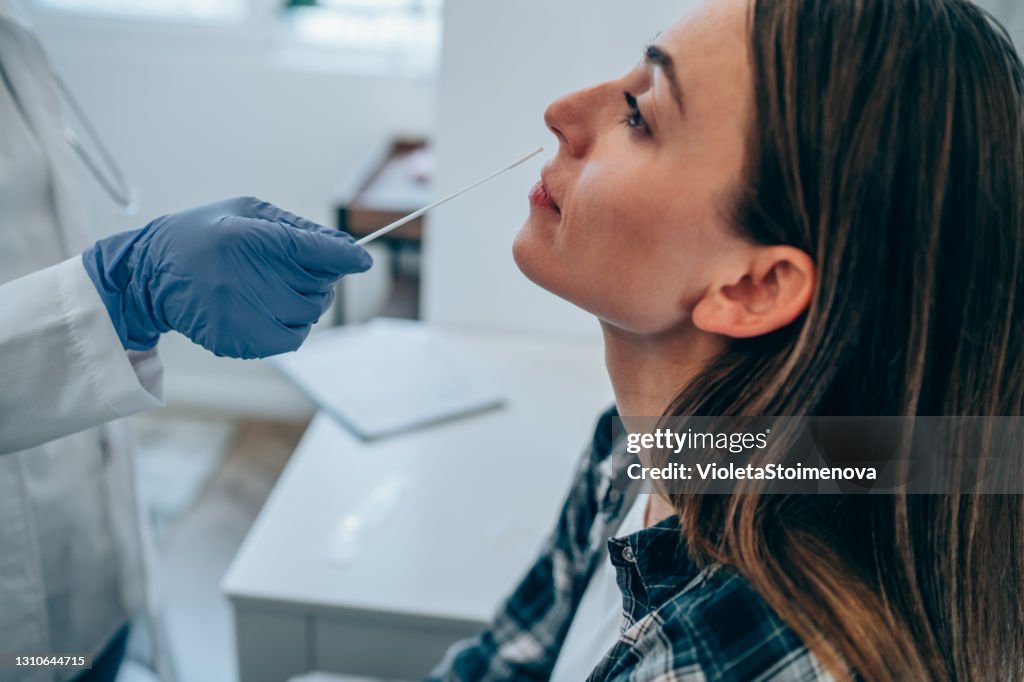 Junge Frau wird in der medizinischen Klinik auf Coronavirus/Covid-19 getestet.