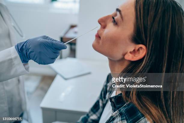 young woman getting tested for coronavirus/covid-19 at medical clinic. - coronavirus stock pictures, royalty-free photos & images