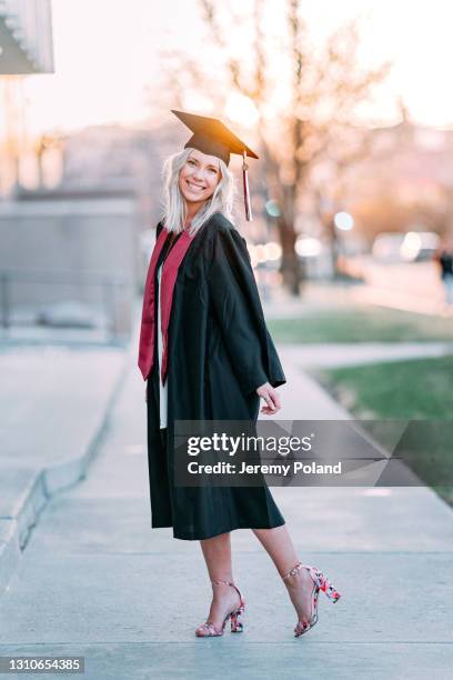 portrait of a happy college university graduate wearing cute high heels and looking at the camera - maroon graduation stock pictures, royalty-free photos & images