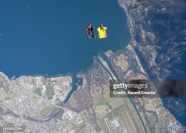 wingsuit fliers soar above swiss mountain landscape - aerial stunts flying stock pictures, royalty-free photos & images