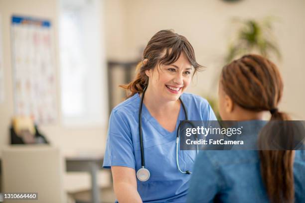 infirmière caucasienne amicale et souriante avec un patient d’enfant - infirmière photos et images de collection