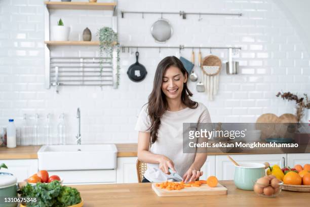 beautiful woman cutting ingredients for a meal in the kitchen - cookery foto e immagini stock