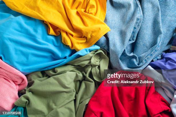 lots of bright dirty colorful scattered clothes, abstract background. the concept of homework, lack of time for household chores. - vestido fotografías e imágenes de stock