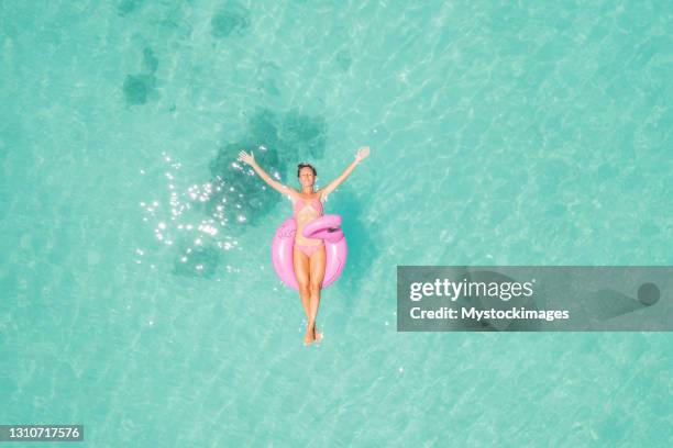 drone view of woman floating on inflatable flamingo - lilo stock pictures, royalty-free photos & images