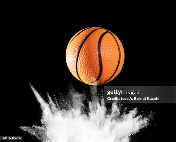 impact and rebound of a ball of basketball on a surface of land and powder on a black background - ballon rebond stock-fotos und bilder