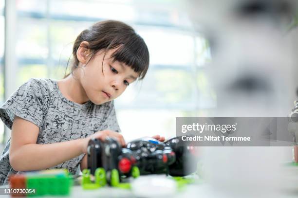 asian preschool girls wearing hearing aids while learning on a robot assembly in classroom. improve kids learning skill and motivative concetps. - genius fotografías e imágenes de stock