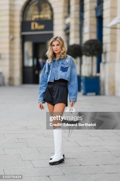 Xenia Adonts wears a blue denim jacket from Valentino, a white and black leather quilted Chanel Gabrielle bag, black shorts from Saint Laurent YSL,...