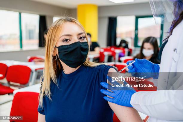 infermiera dà agli studenti una vaccinazione a scuola durante la pandemia di coronavirus - boys foto e immagini stock