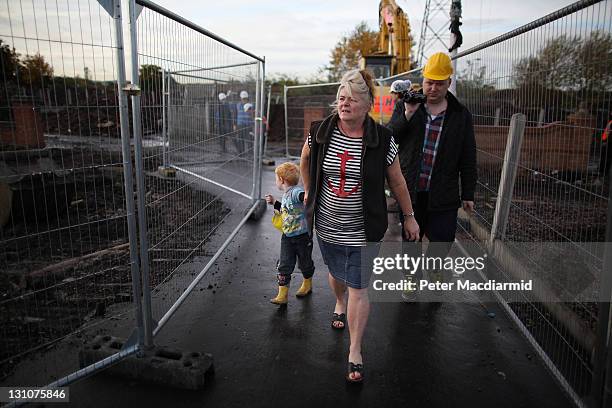 Resident Margaret McCarthy is filmed by a friend as she walks to her house at Dale Farm travellers camp with her son Daniel past cleared areas on...