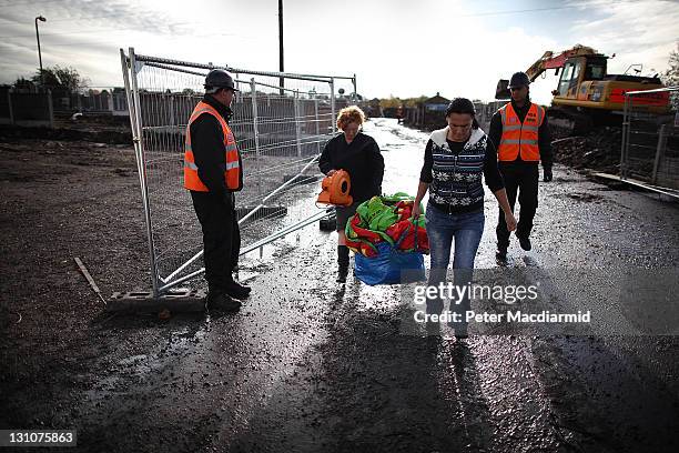 Resident Maime Slattery helps a friend remove a bag of clothes from a house at Dale Farm travellers camp watched by security guards on November 1,...