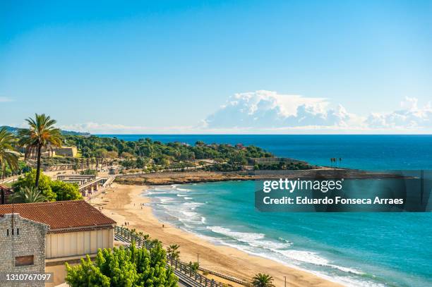 view of the platja del miracle (miracle beach) and the mediterranean sea, with the ruins of the reina and sant jordi forts on the background - tarragona stock pictures, royalty-free photos & images