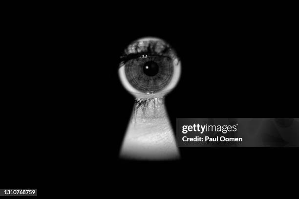 human eye peeking through a keyhole. - key hole stock pictures, royalty-free photos & images