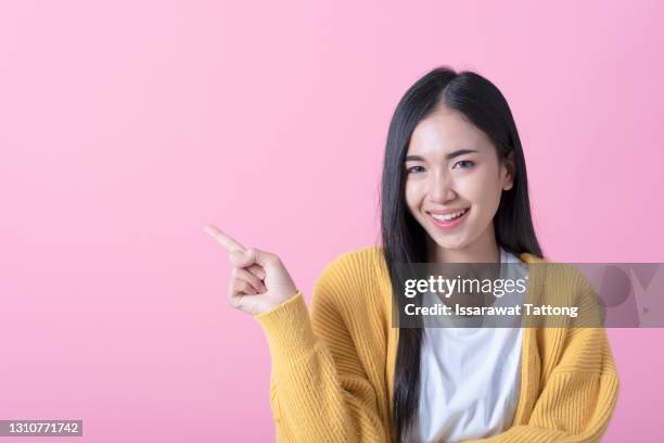 young woman over isolated pink background pointing finger to the side - mit dem finger zeigen stock-fotos und bilder