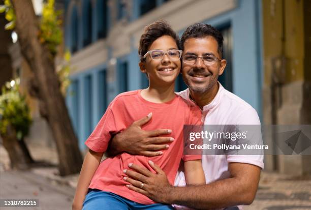 father and son sitting on park bench - son stock pictures, royalty-free photos & images