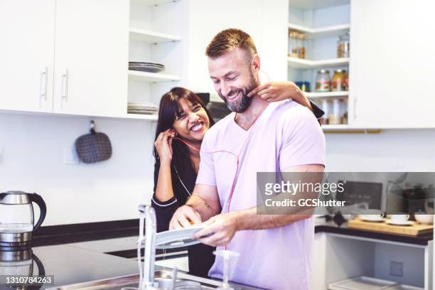 esposa burlándose de ella hushabd mientras él está limpiando los platos - expatriado fotografías e imágenes de stock