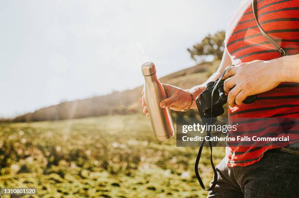 male holding a water-bottle and a pair of binoculars outside - sapato metalizado imagens e fotografias de stock