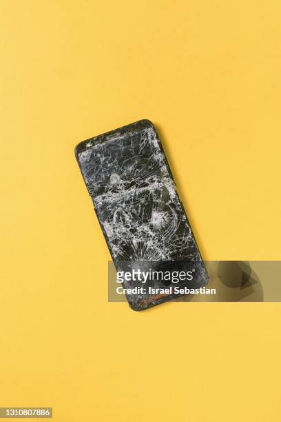 top view of a broken cell phone on a yellow background. - fracture stock-fotos und bilder