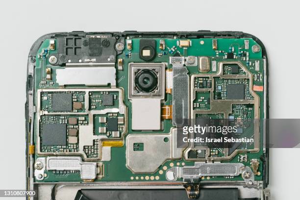 top view of the circuitry and internal board of a mobile phone that has been broken by a fall on a white background. - disassemblare foto e immagini stock