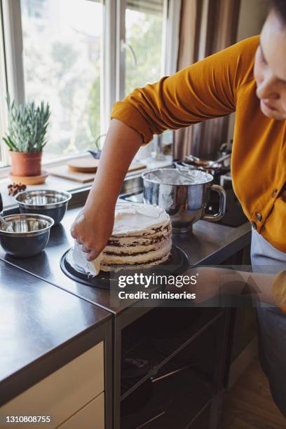 anonymous young woman spreading whipped cream on the cake - white fudge stock pictures, royalty-free photos & images