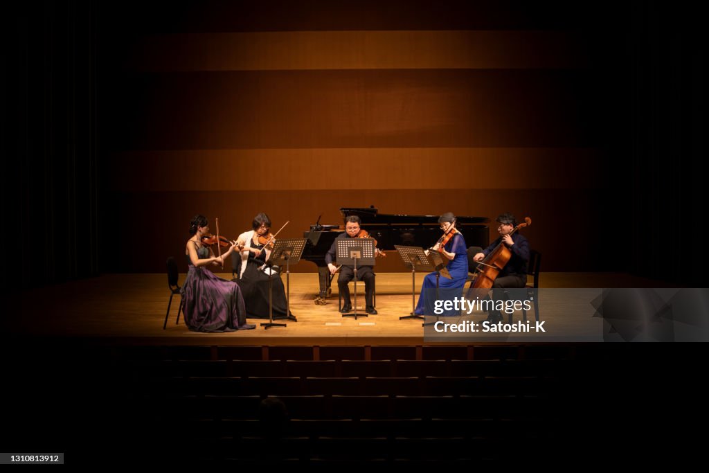 Five musicians playing violin, viola, and cello at classical music concert