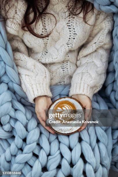 woman covered with blanket holding mug of hot coffee. - gezellig stockfoto's en -beelden