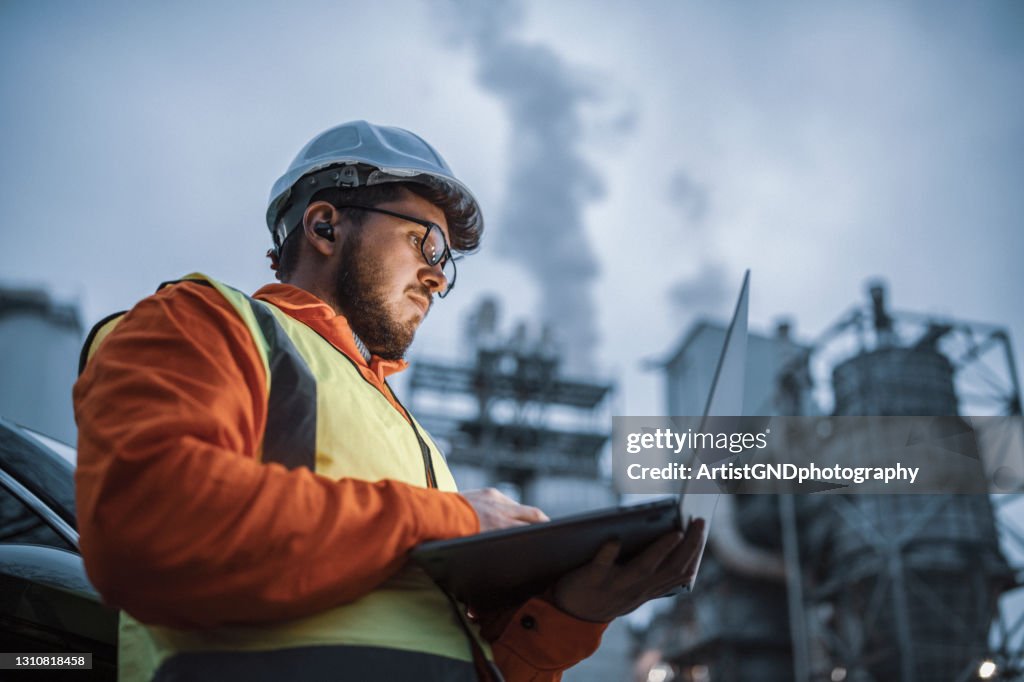 Serious handsome engineer using a laptop while working in the oil and gas industry.