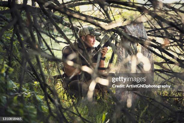hombre oculto en camuflaje cazando animales con rifle de ándape. - hunting fotografías e imágenes de stock