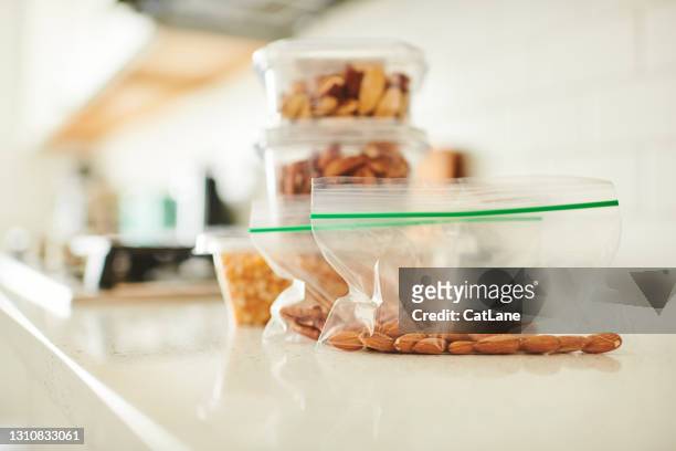noci assortite in contenitori di plastica su un bancone in una cucina moderna e luminosa - snack foto e immagini stock