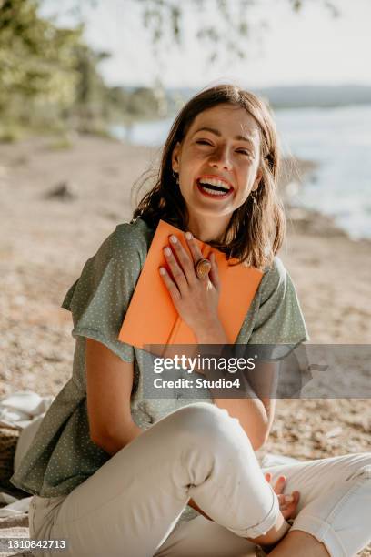 weibliche lachen beim lesen ihres tagebuchs - beach book reading stock-fotos und bilder
