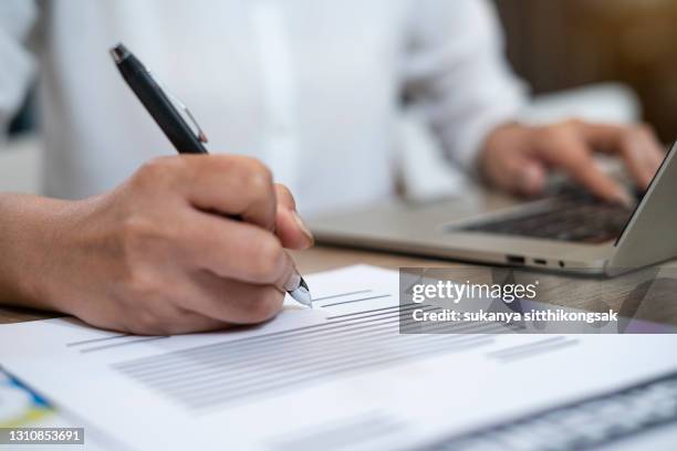 close up of hand asian businesswoman writing on paper and using laptop  for working. - form stock pictures, royalty-free photos & images