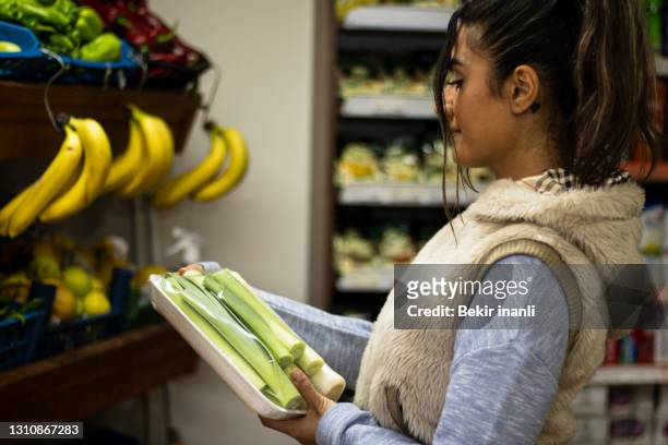 スーパーマーケットの野菜セクションでミルクラベルをチェックする女性 - use by label ストックフォトと画像
