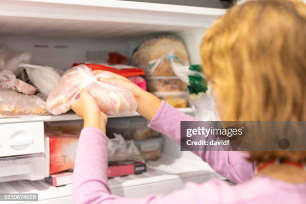 teenager putting meat in a freezer - refrigerator stock pictures, royalty-free photos & images
